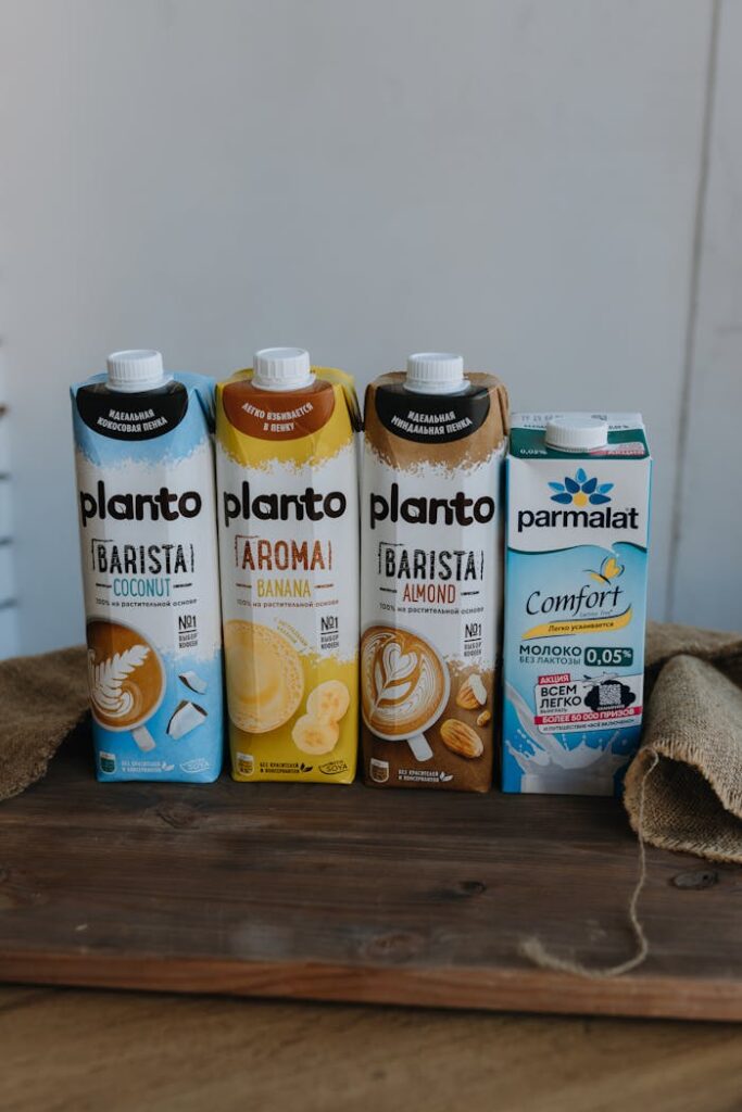 Assorted plant-based milk cartons featuring coconut, banana, and almond flavors on a rustic wooden table.